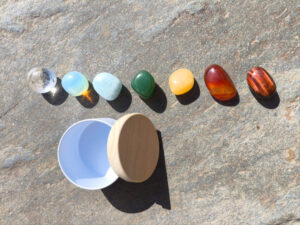 Piedras pulidas del set para los chakras presentadas junto a cuenco sobre superficie de piedra