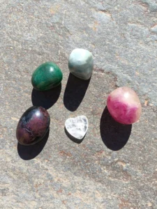 Piedras pulidas del set de Capricornio con granate, aventurina, amazonita, fluorita y cuarzo dispuestas sobre superficie de piedra