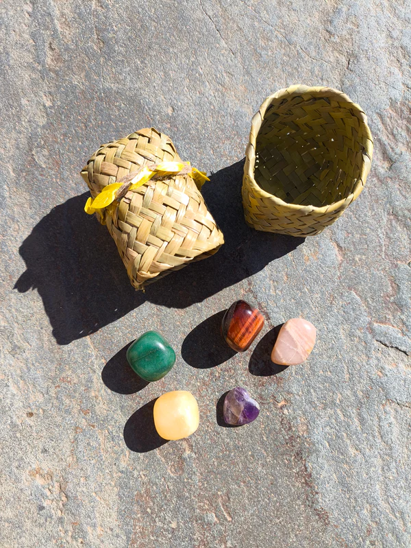 Set de Sagitario con piedras pulidas presentadas junto a cesta sobre superficie de piedra