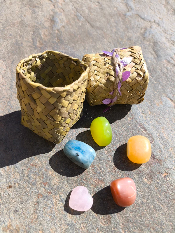 Set de Géminis con piedras pulidas dispuestas junto a cuenco natural sobre superficie de piedra