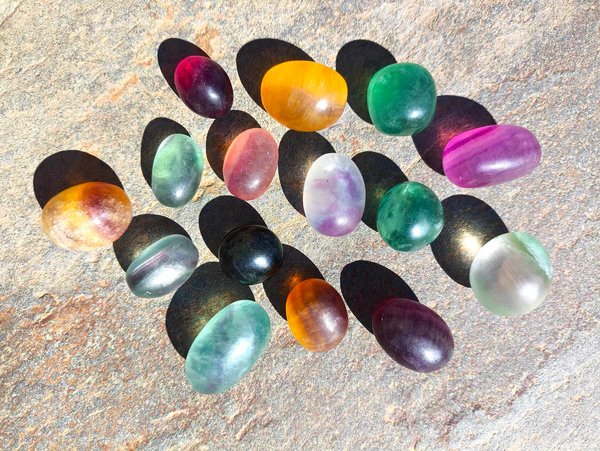 Fluorita pulida natural con variaciones de color dispuesta en conjunto sobre piedra