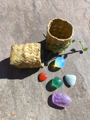 Set de Acuario con cornalina, opalita, fluorita, amatista y aguamarina pulidos presentados junto a cesta natural sobre superficie de piedra