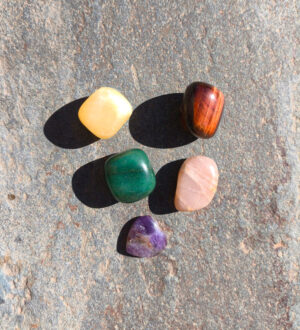 Piedras pulidas del set de Sagitario con topacio, ojo de toro, aventurina, piedra luna y amatista dispuestas sobre piedra