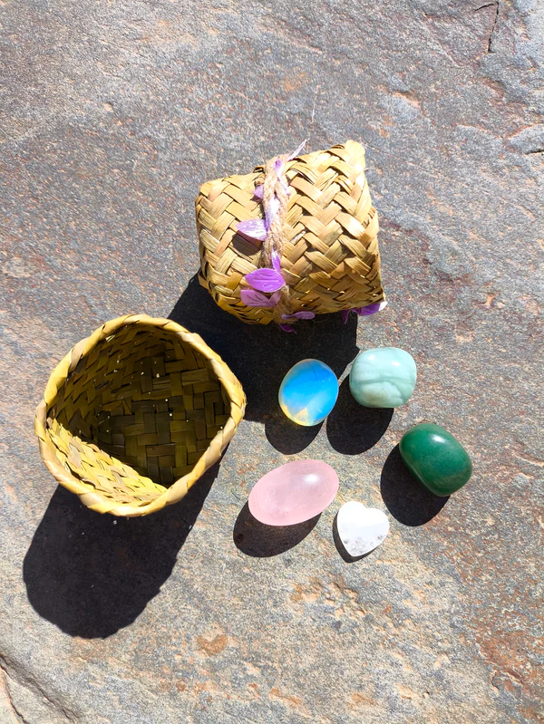 Set de Piscis con piedras pulidas presentadas junto a cesta natural sobre superficie de piedra