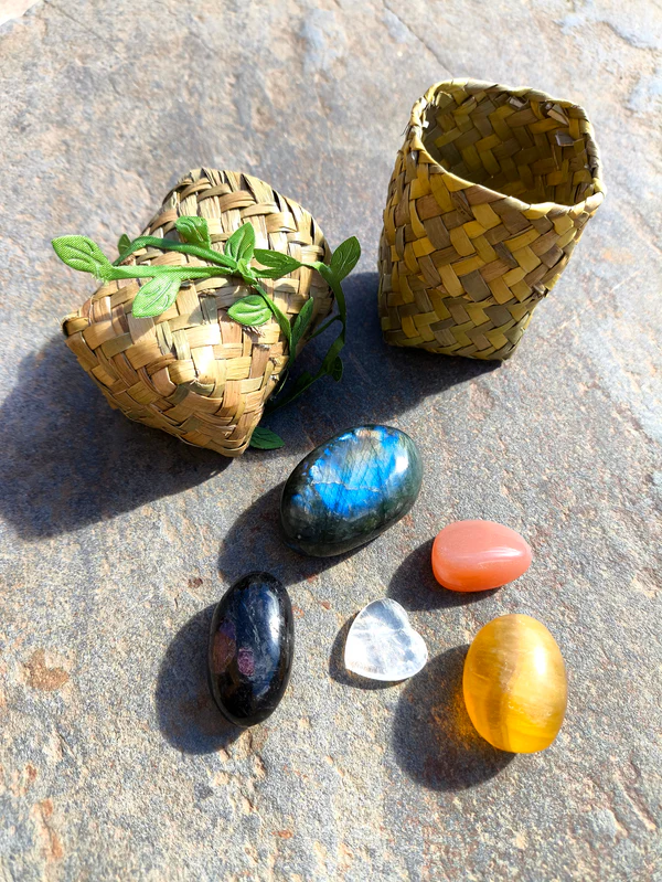 Set de Escorpio con granate, labradorita, cuarzo, piedra luna y fluorita pulidos presentados junto a cuenco natural sobre superficie de piedra