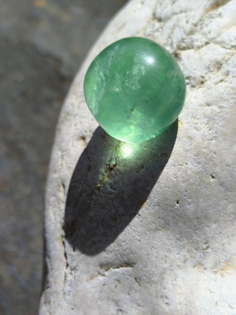 Piedra Fluorita verde pulida capturada en luz natural sobre roca clara; cristal del Set para Acuario asociado a claridad mental, enfoque y equilibrio energético para signos de aire.