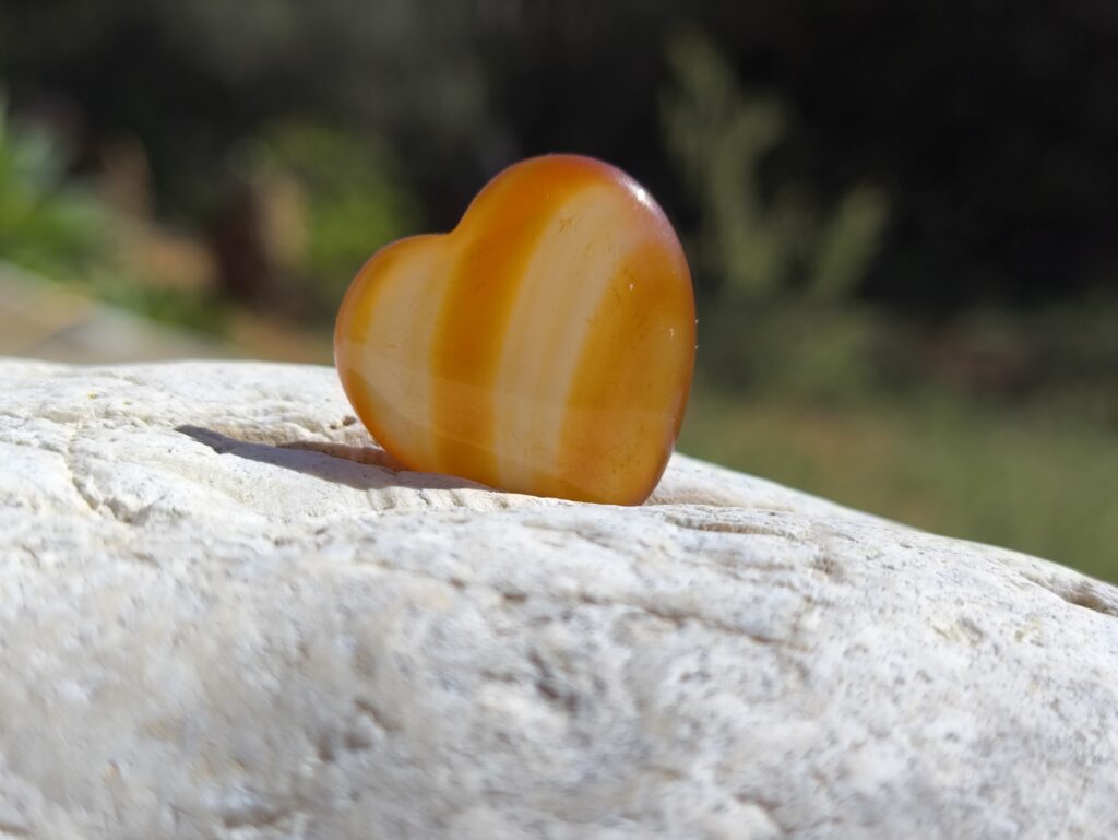 Piedra pulida de color naranja apoyada sobre roca clara en entorno natural