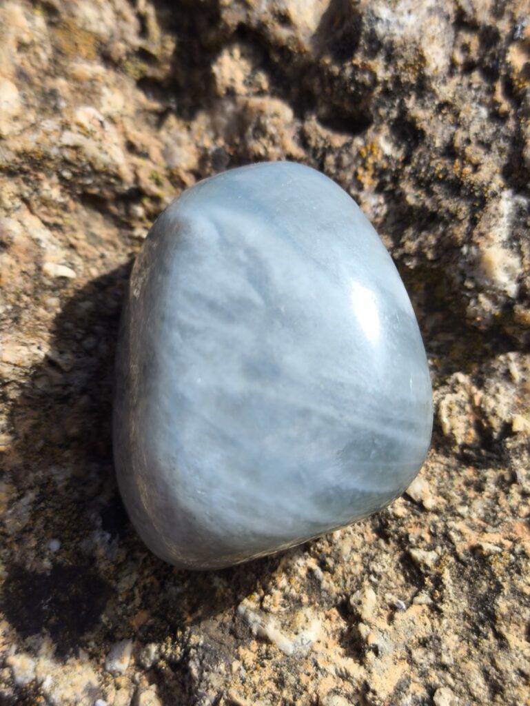 Piedra de aguamarina azul claro sobre roca, iluminación natural — cristal para serenidad y comunicación auténtica.