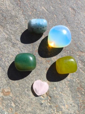 Piedras pulidas del set de Tauro con aventurina, amazonita, opalita, jade y cuarzo rosa dispuestas sobre superficie de piedra