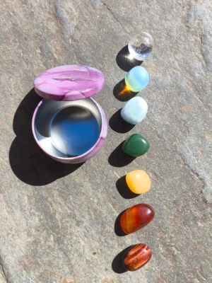 Set para los chakras con piedras pulidas dispuestas junto a cuenco sobre superficie de piedra