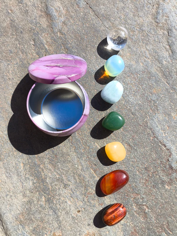Set para los chakras con piedras pulidas dispuestas junto a cuenco sobre superficie de piedra