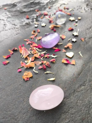 Composición con cuarzo rosa y amatista pulidos dispuestos sobre piedra con pétalos decorativos