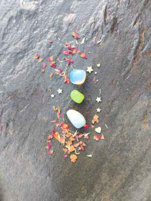 Piedras pulidas dispuestas en vertical sobre superficie de piedra con pétalos y elementos decorativos