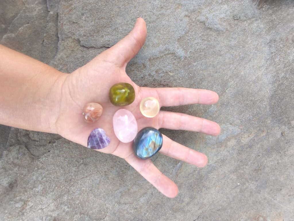 Mano sosteniendo piedras pulidas de colores sobre fondo natural