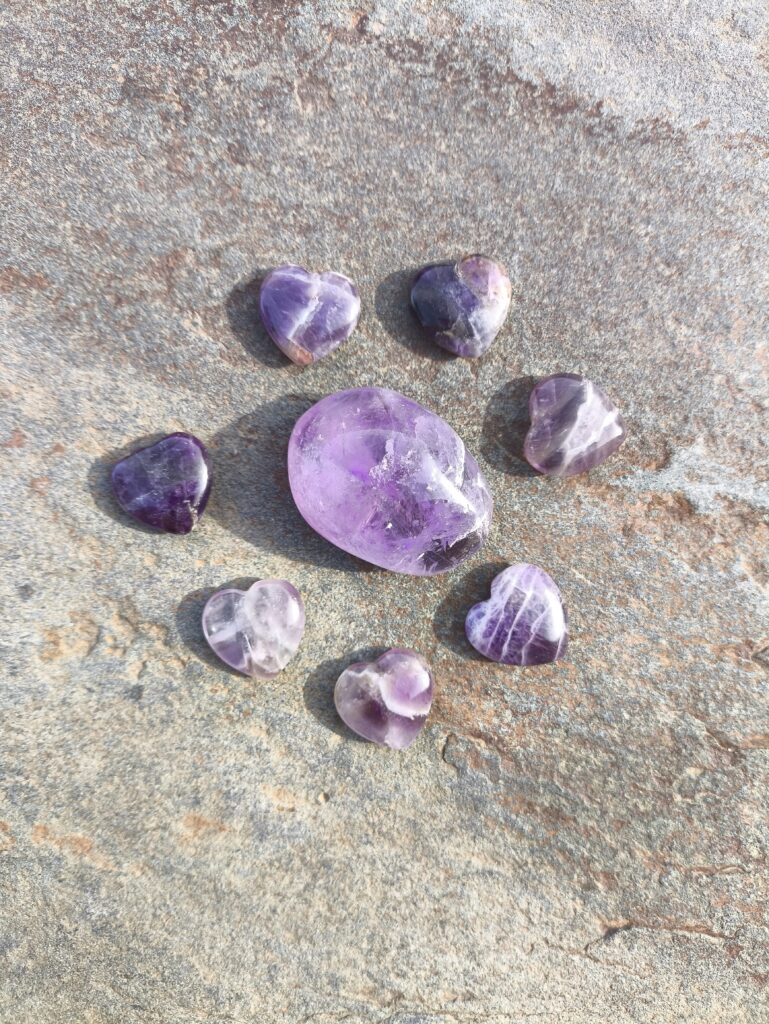 Amatista natural en diferentes formas y tamaños dispuesta sobre superficie de piedra